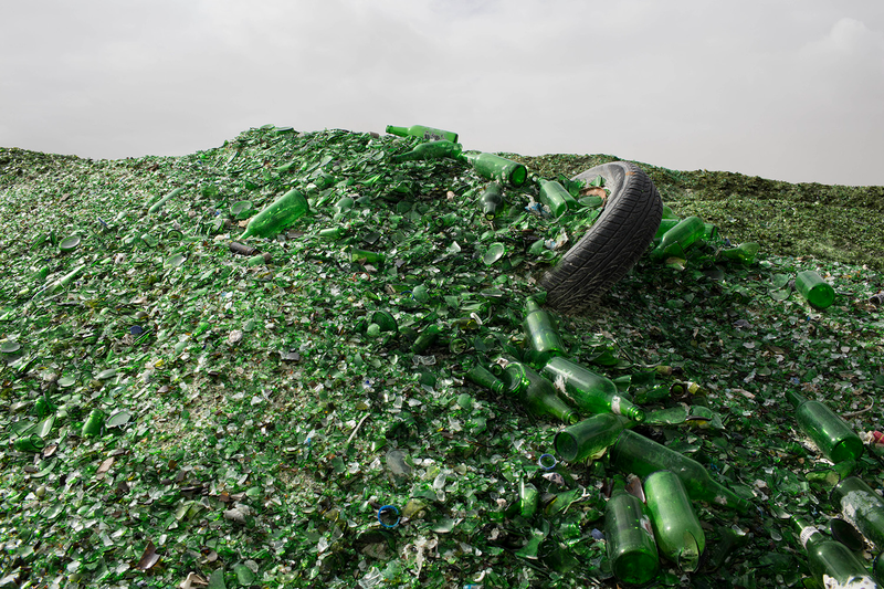 A tire hides in a hill made of green glass bottles.